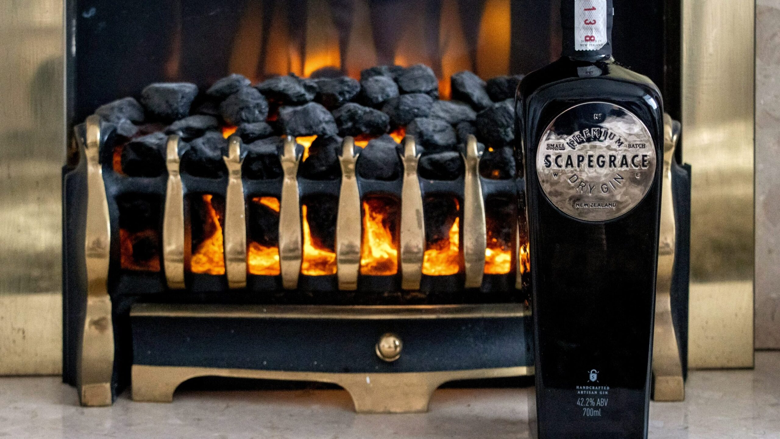 Black bottle of gin in front of fireplace.