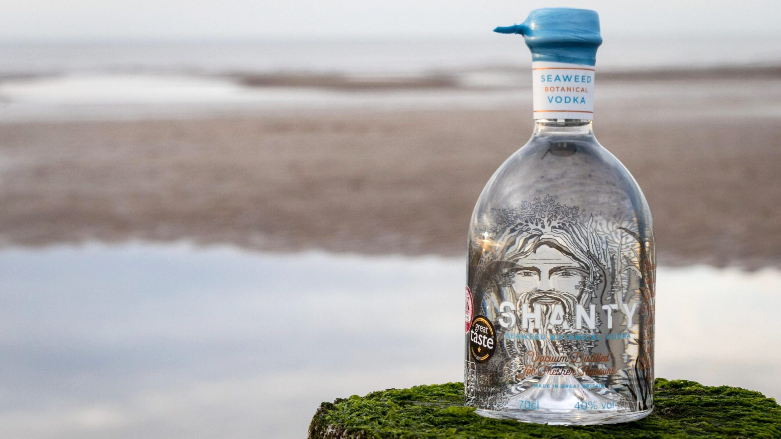 Bottle of seaweed vodka on beach.