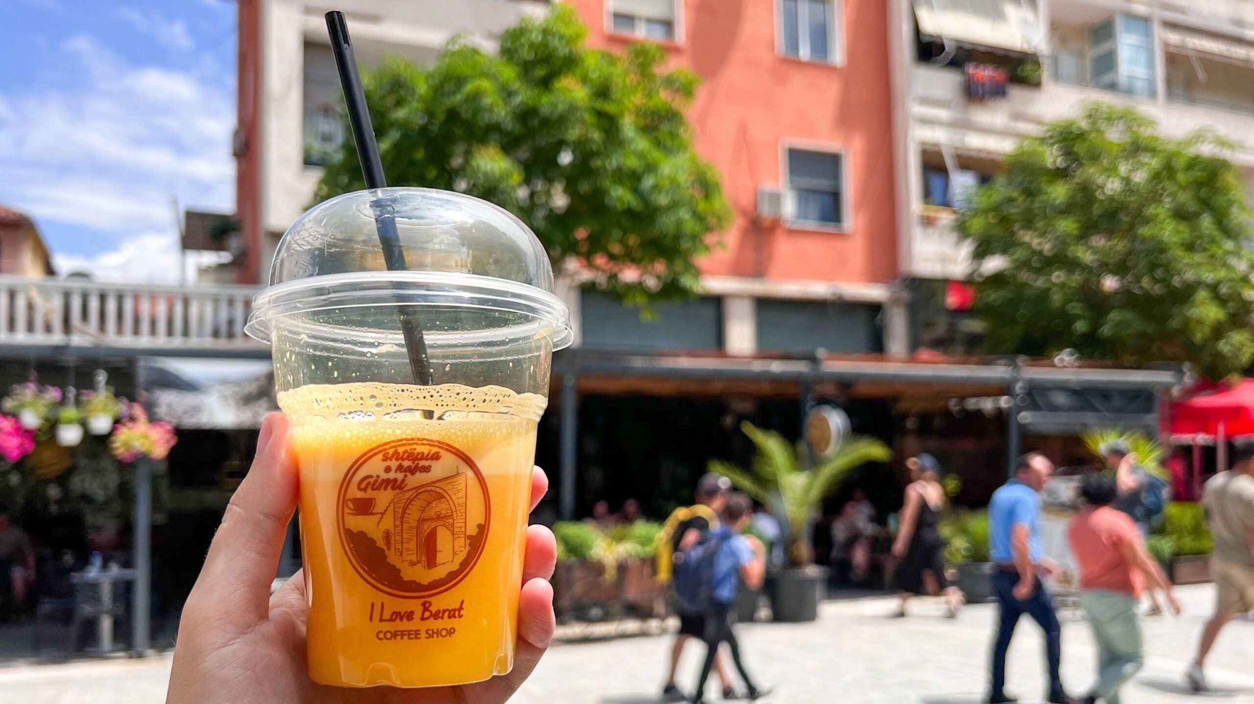 Cup of fresh orange juice held in street.