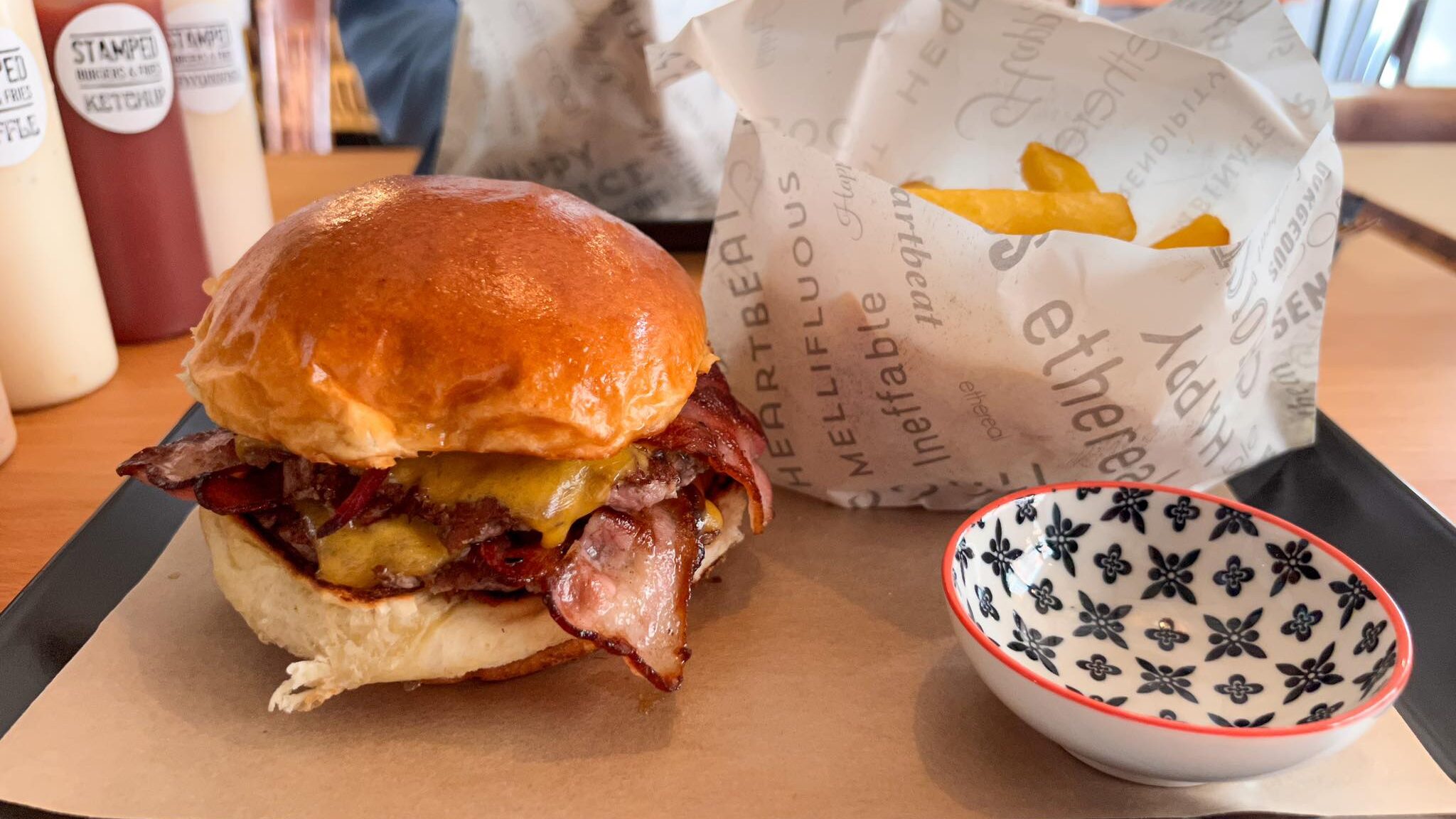 Smash burger with bacon and side of fries.