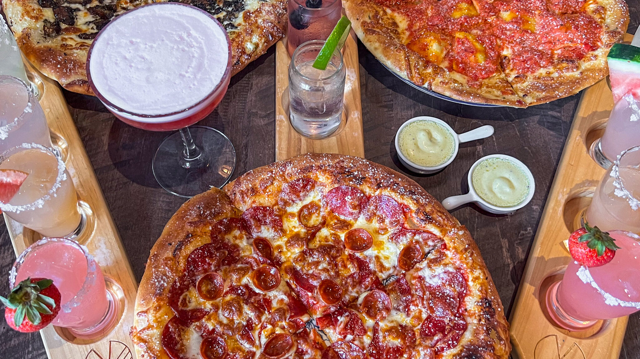 Three large loaded pizzas with cocktails. 