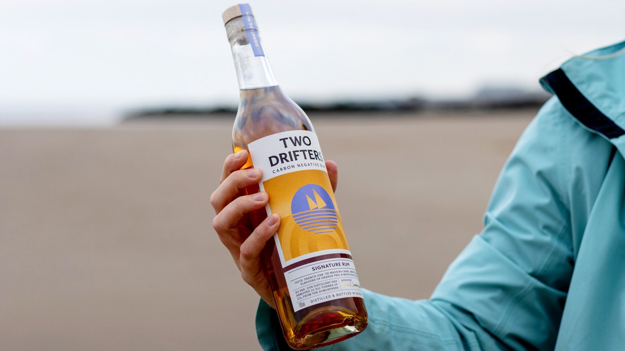 Bottle of rum held up on beach.