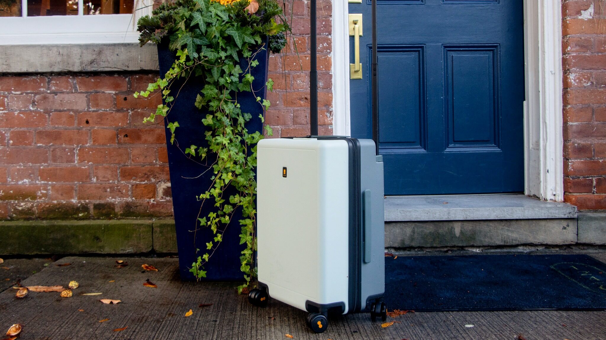 Light green carry-on in front of hotel door.