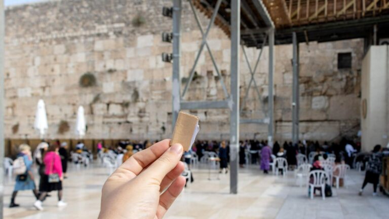 Paper held up in front of Western Wall.