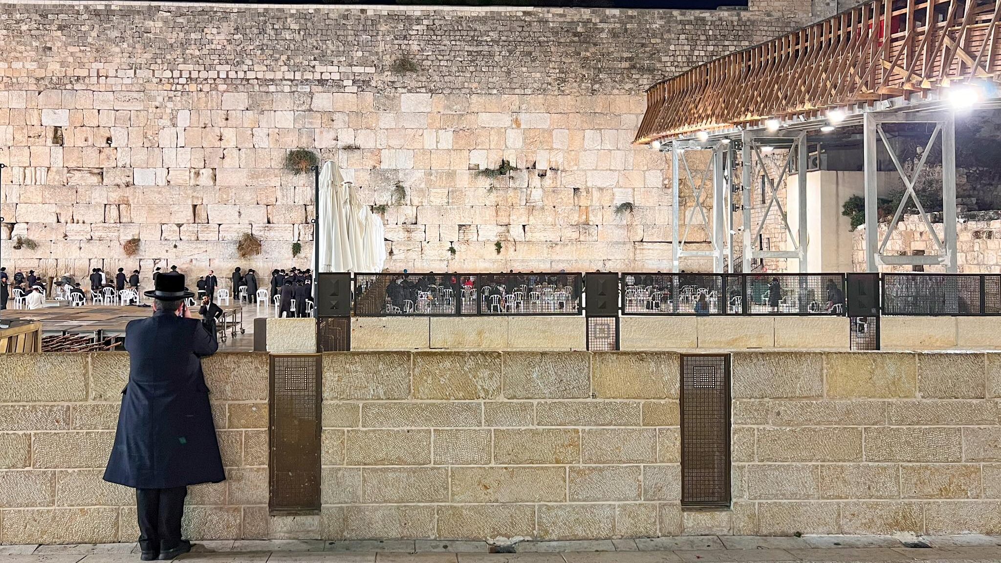 Jewish man looking at the Western Wall at night.