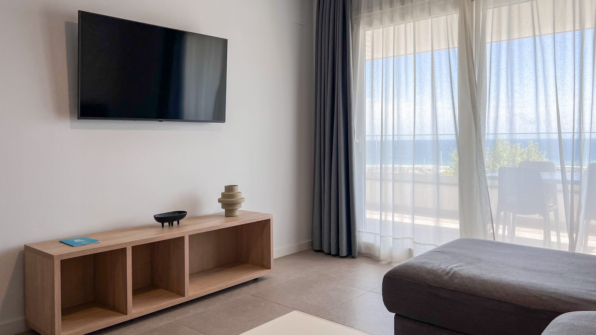 Seating area with TV next to patio with sea view.