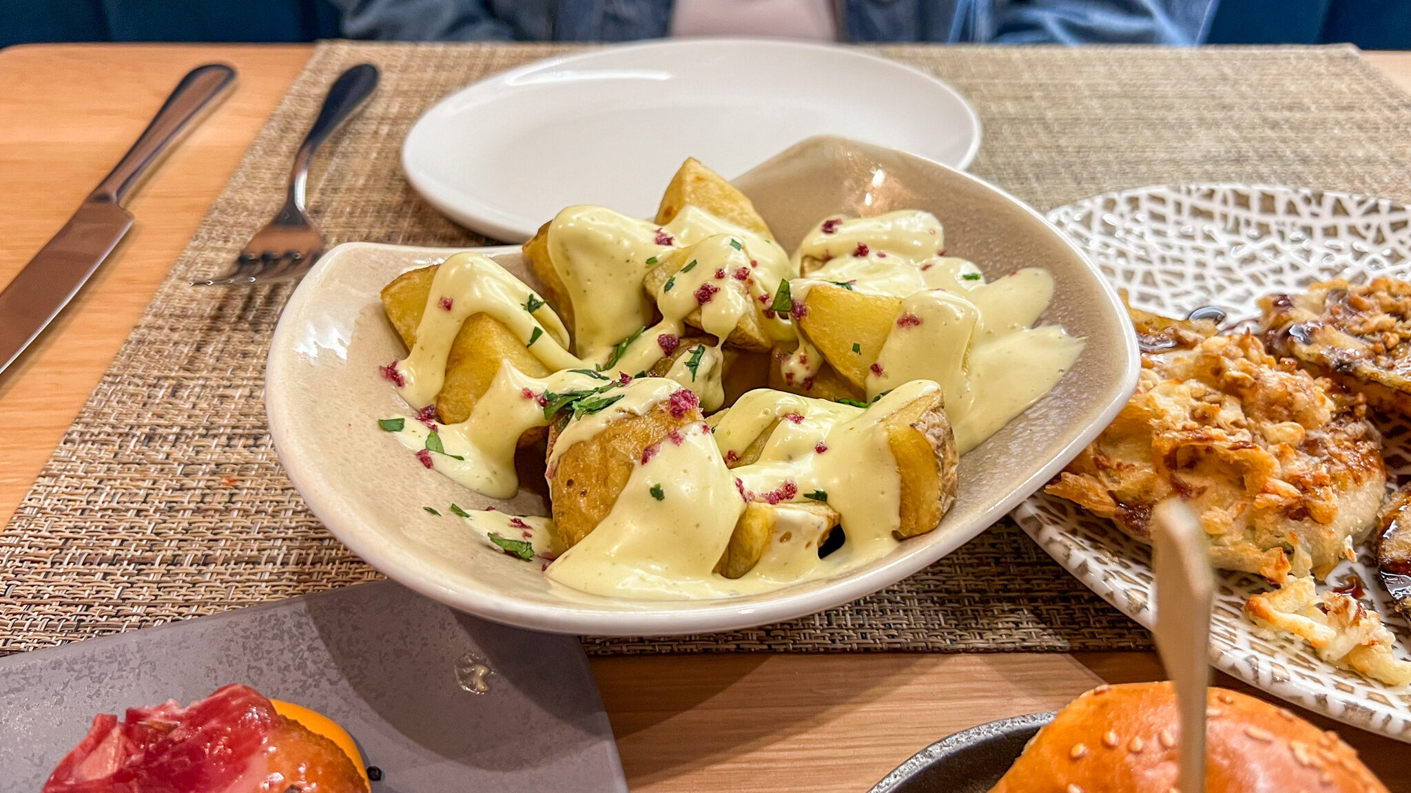 Potatoes covered in white sauce at tapas bar.