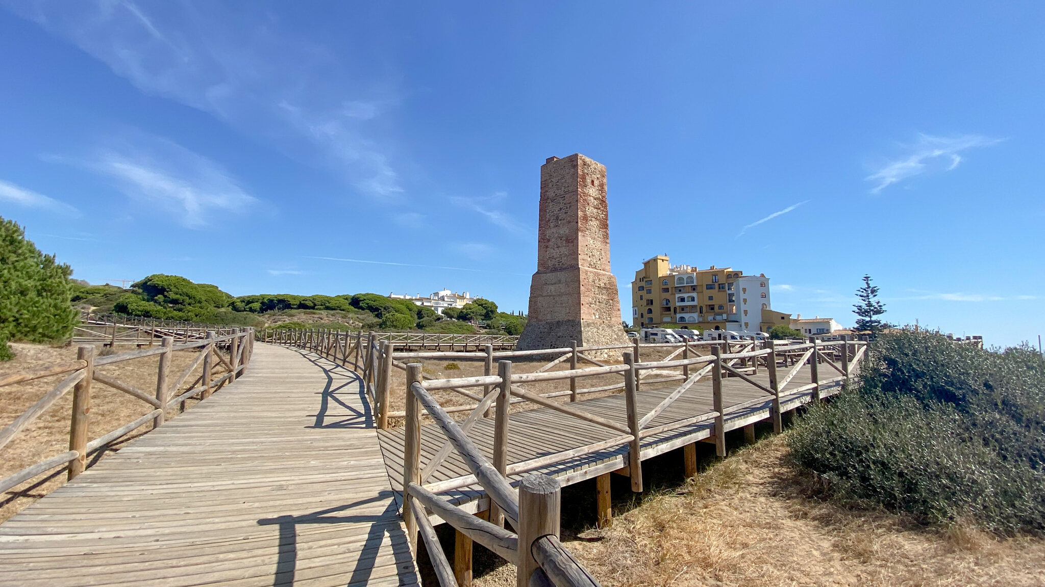 Boardwalks on top of dunes with stone watchtower. 