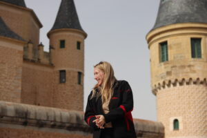 Blonde girl standing in front of castle.