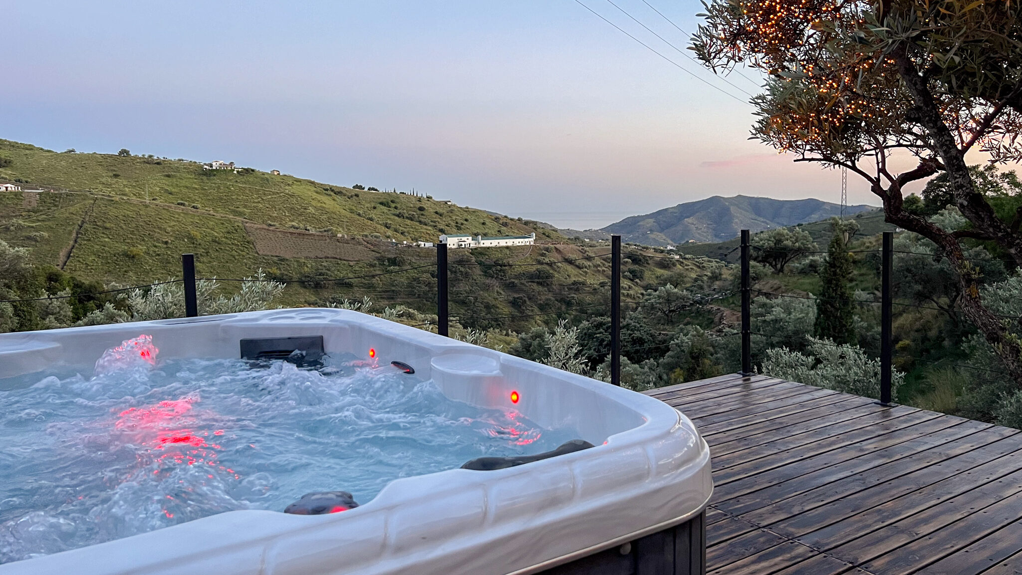 Jacuzzi with lights on deck at sunset.