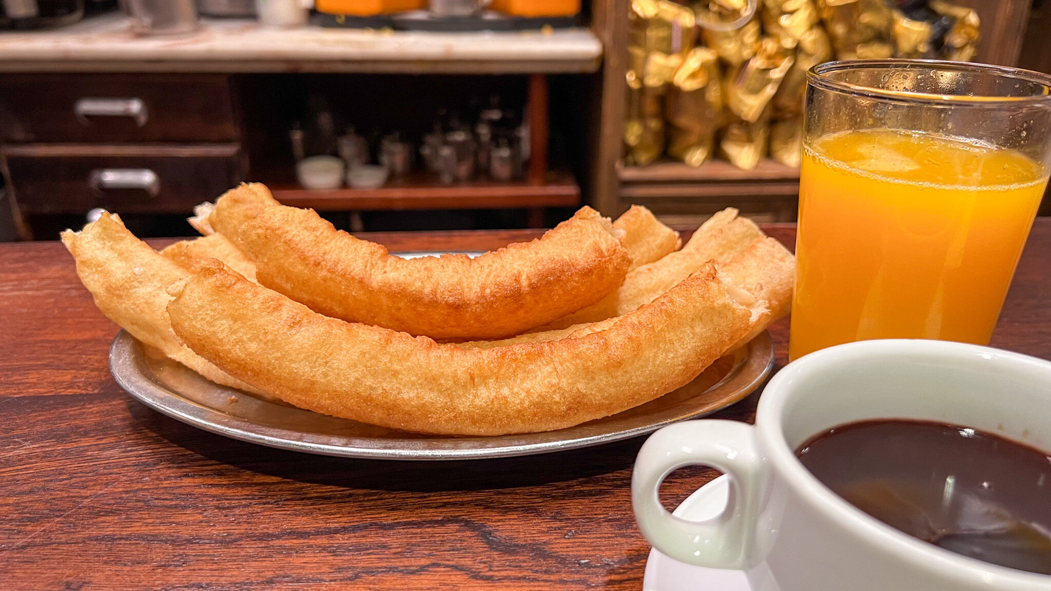 Plate of churros with chocolate and orange juice.