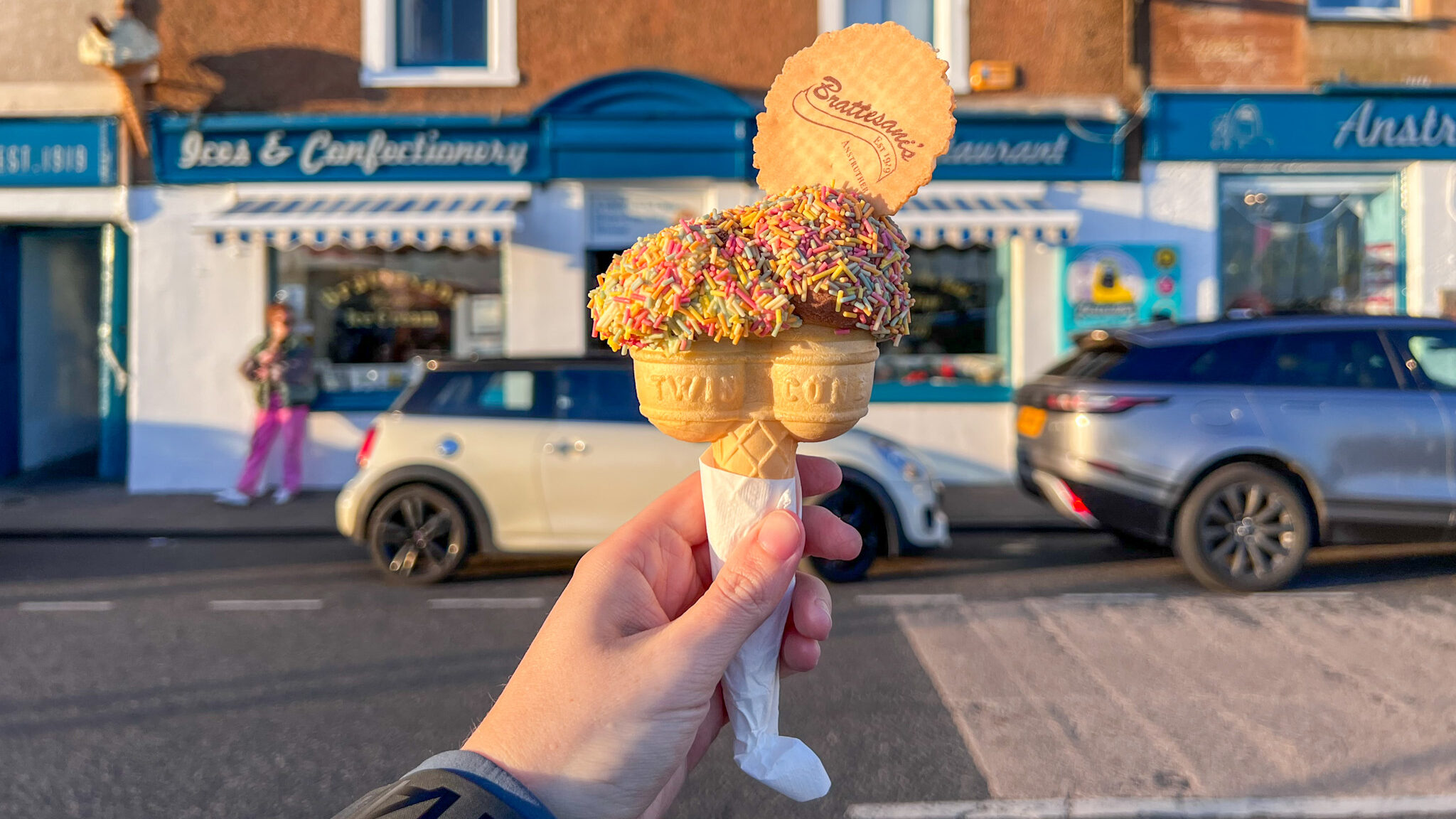 Double ice cream cone in front of shop.