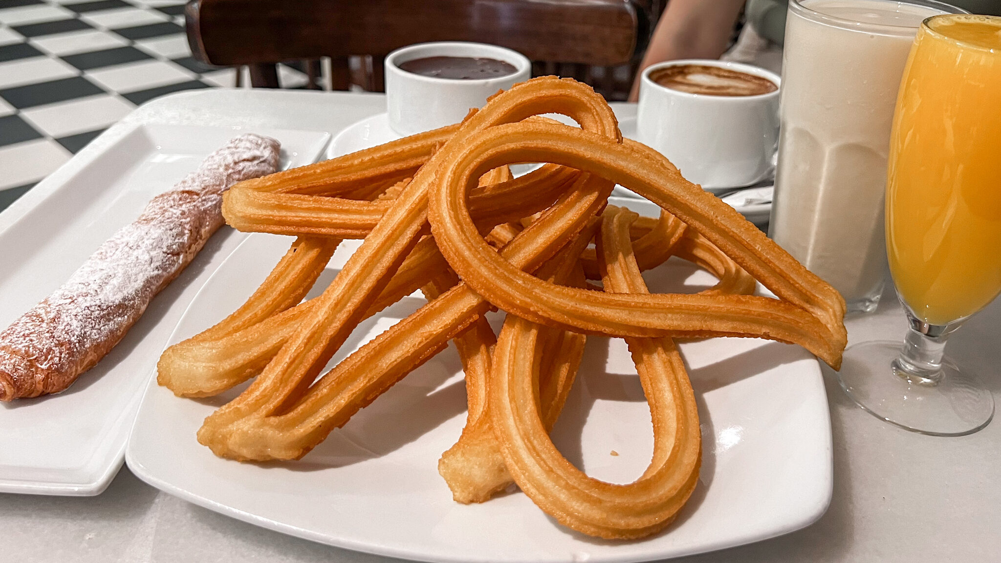 Plate of churros with chocolate and orange juice.