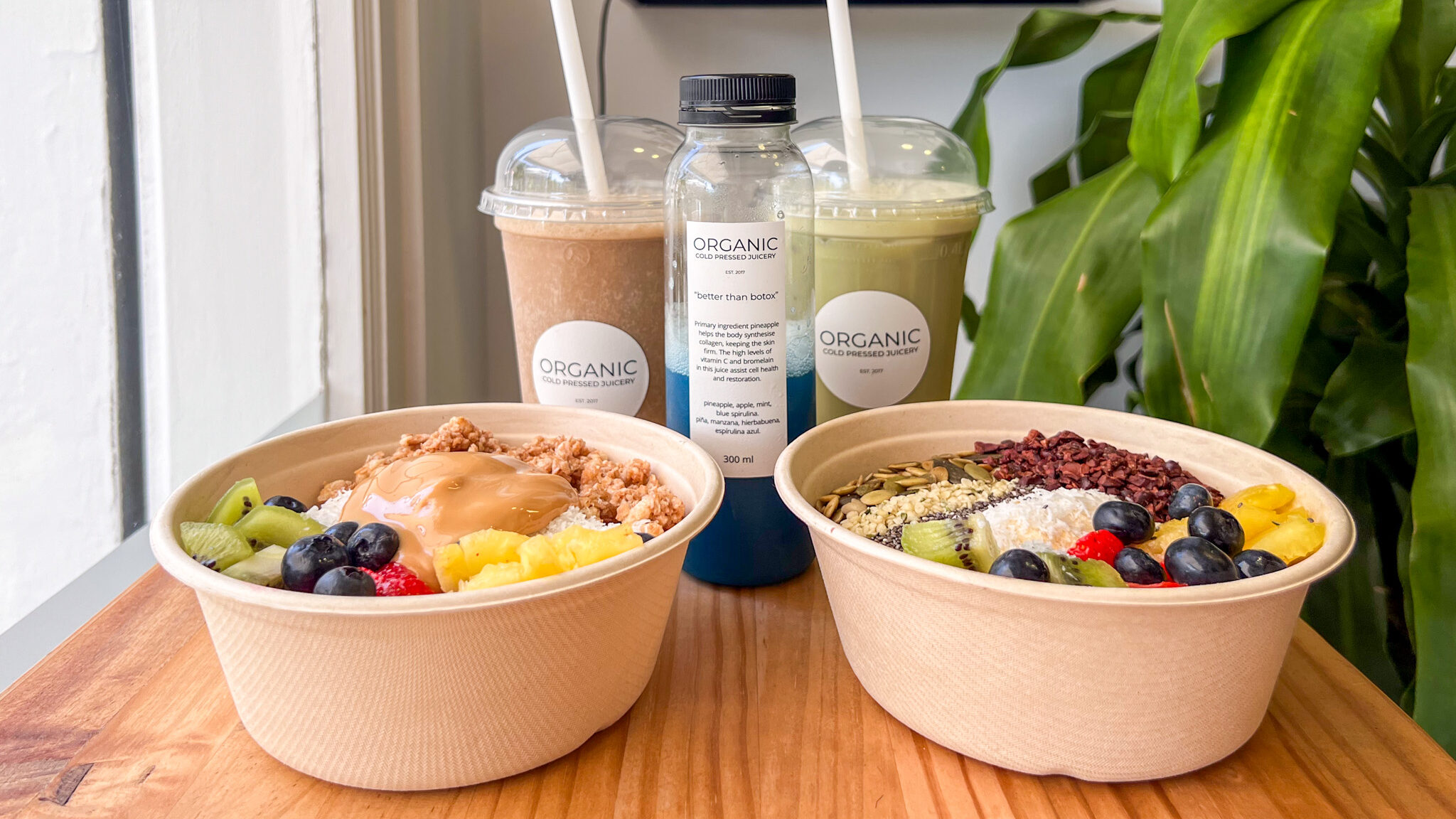 Two acai bowls with iced coffees and juice.