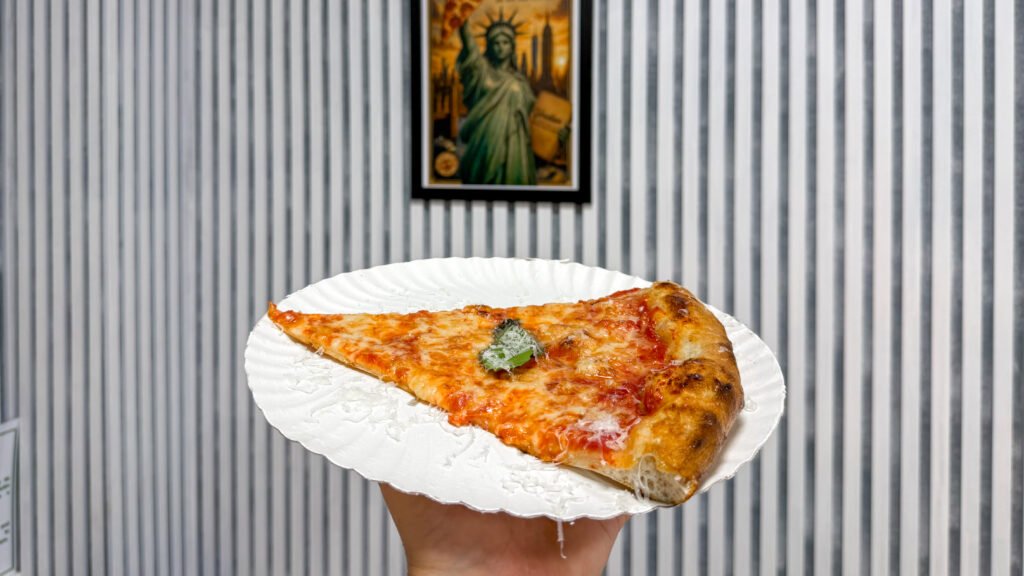 Veridian Pizza Malaga | Krista the Explorer Slice of margarita pizza on white paper plate.