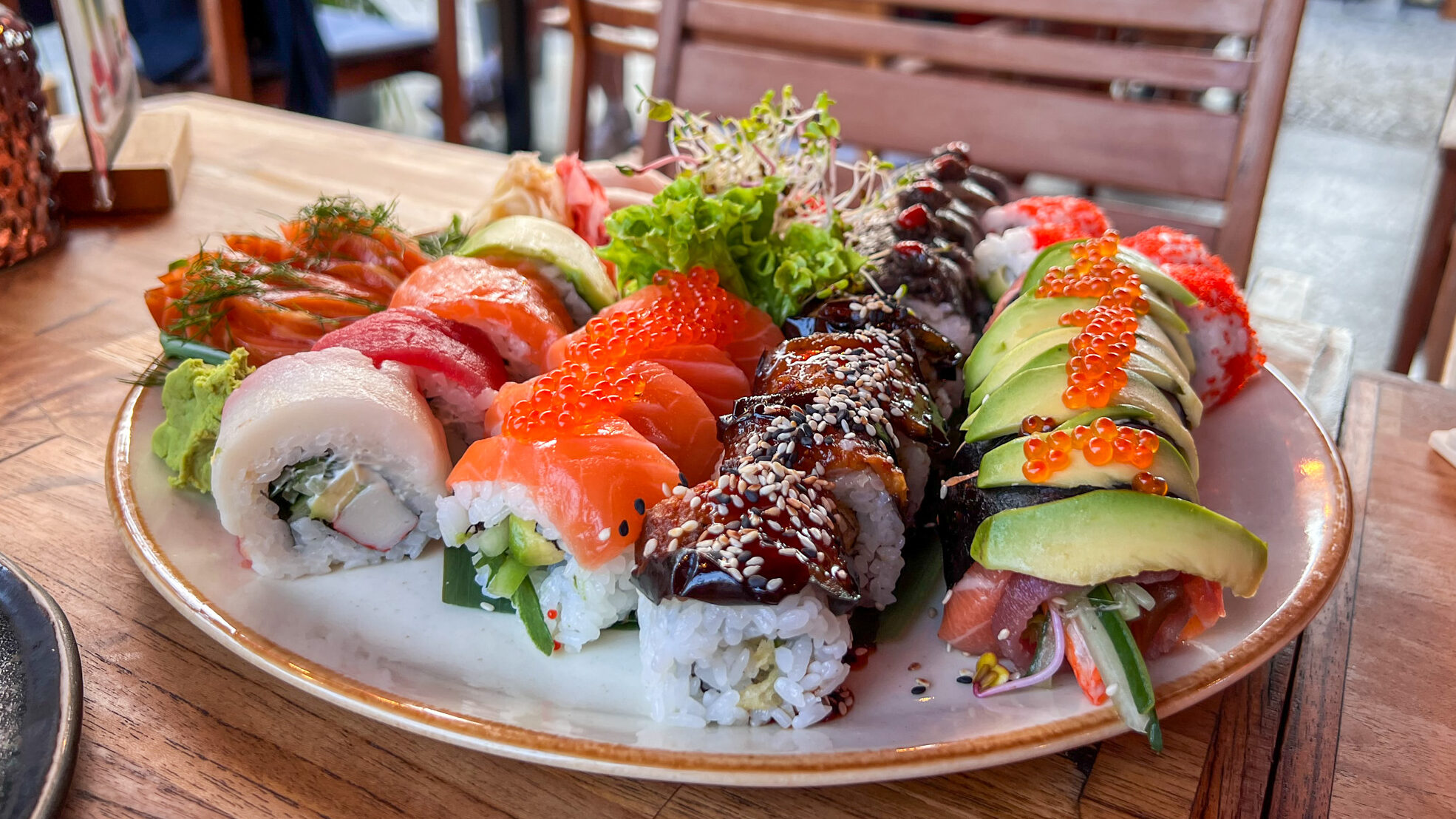 Plate of colourful sushi on outdoor table.