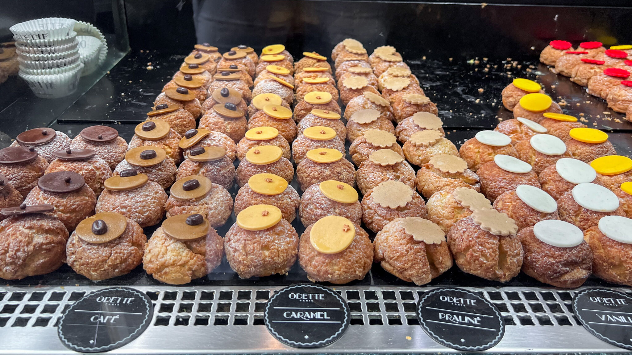 Cream puff pastries lined up in display case.