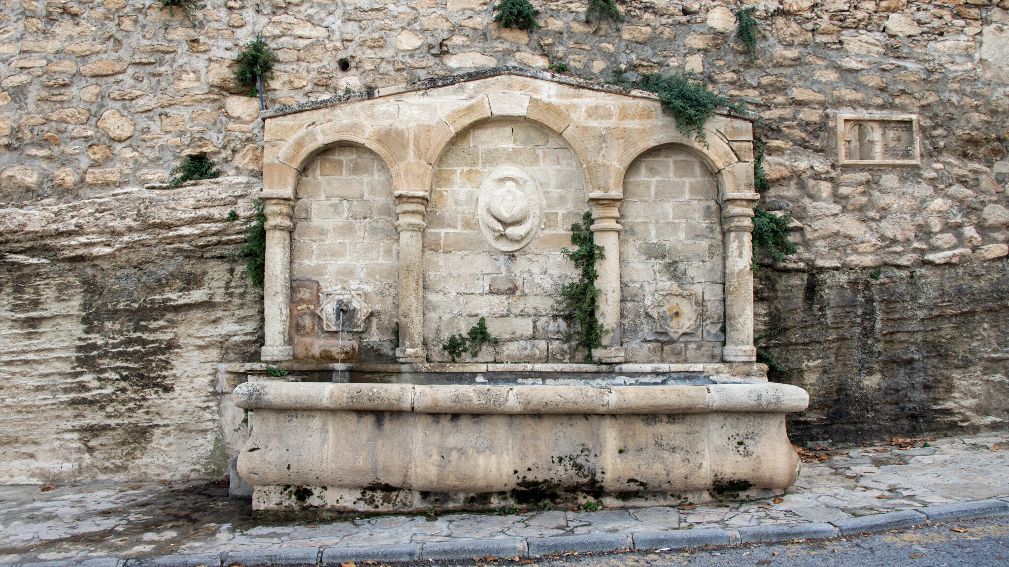 Old stone fountain at entrance to village.