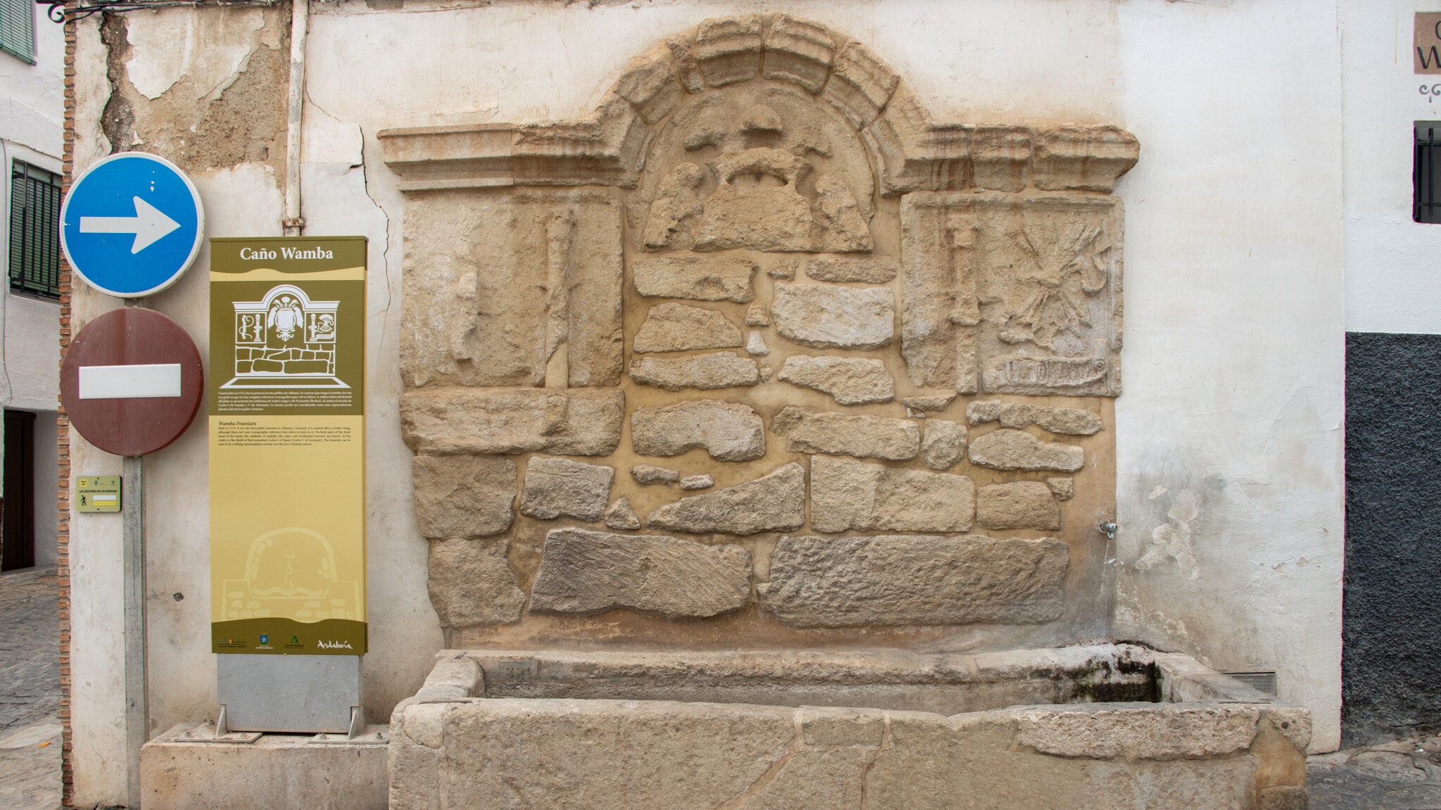 Small stone fountain against white wall.