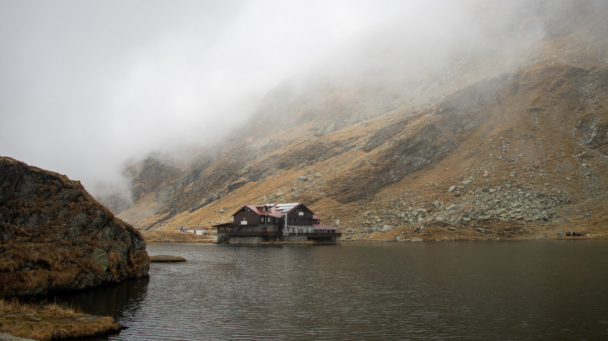 Balea Lake Romania | Krista the Explorer Small lake at top of mountains on foggy day.