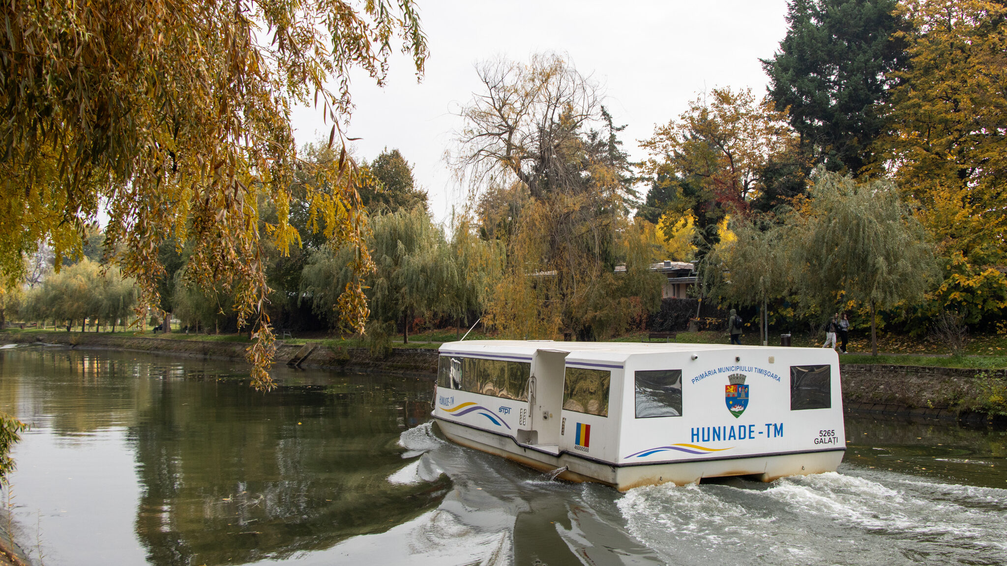 Boat moving along Bega River in autumn. 