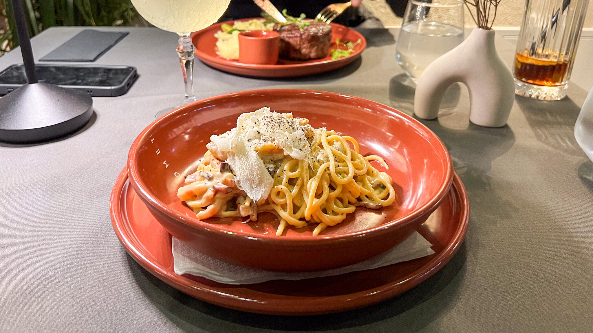 Fresh carbonara in orange bowl at restaurant.