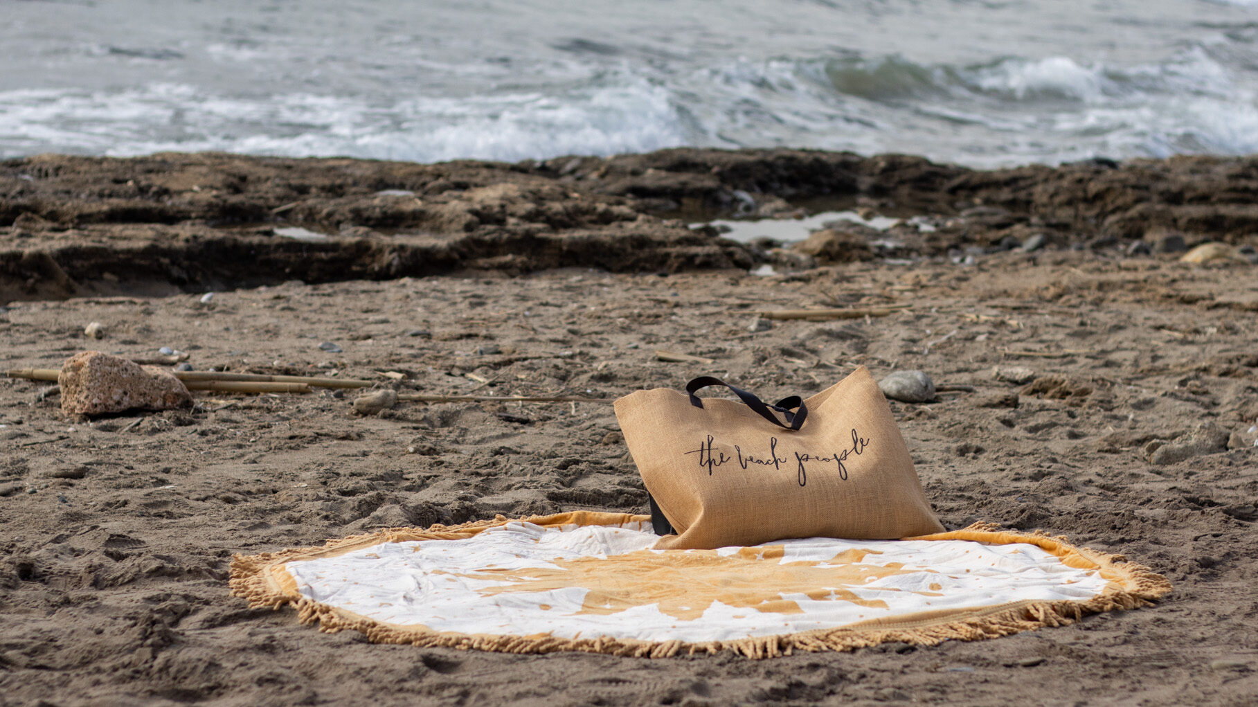 Round beach towel and tote bag at beach.