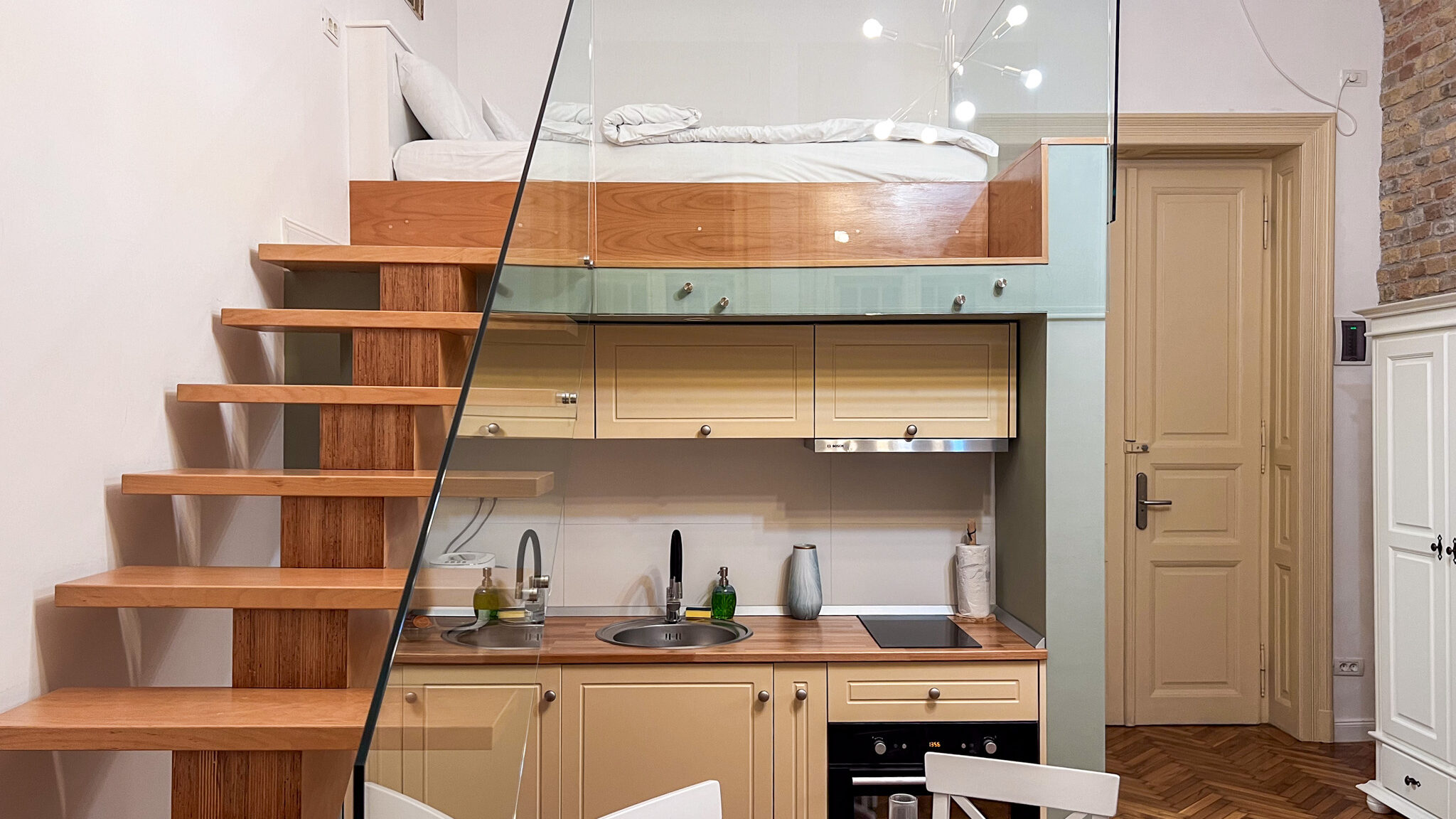 Elevated bed with kitchen below in apartment.