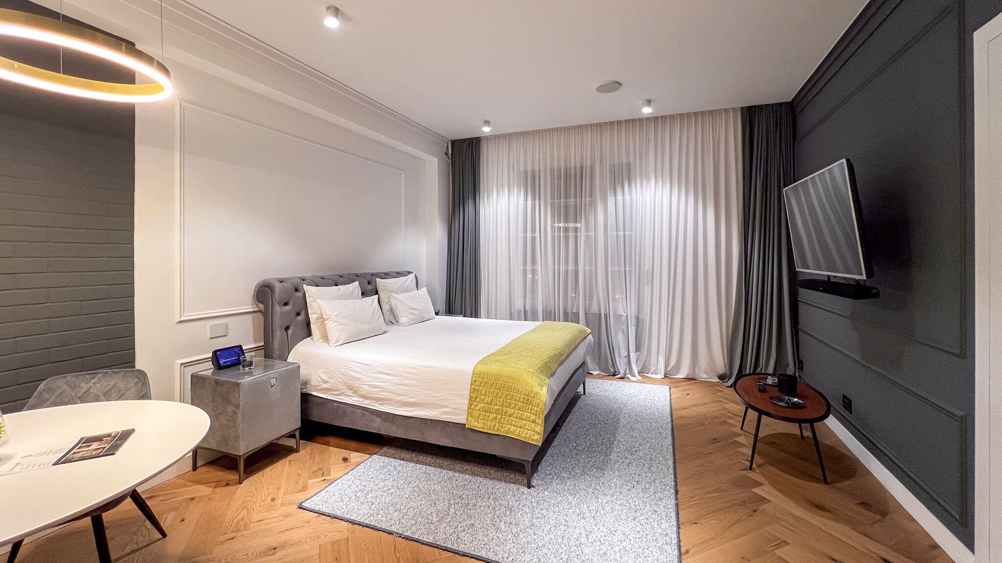 Large bedroom with TV and round table.