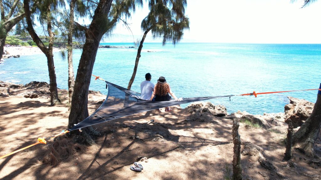 Triangular hammock in front of beach.