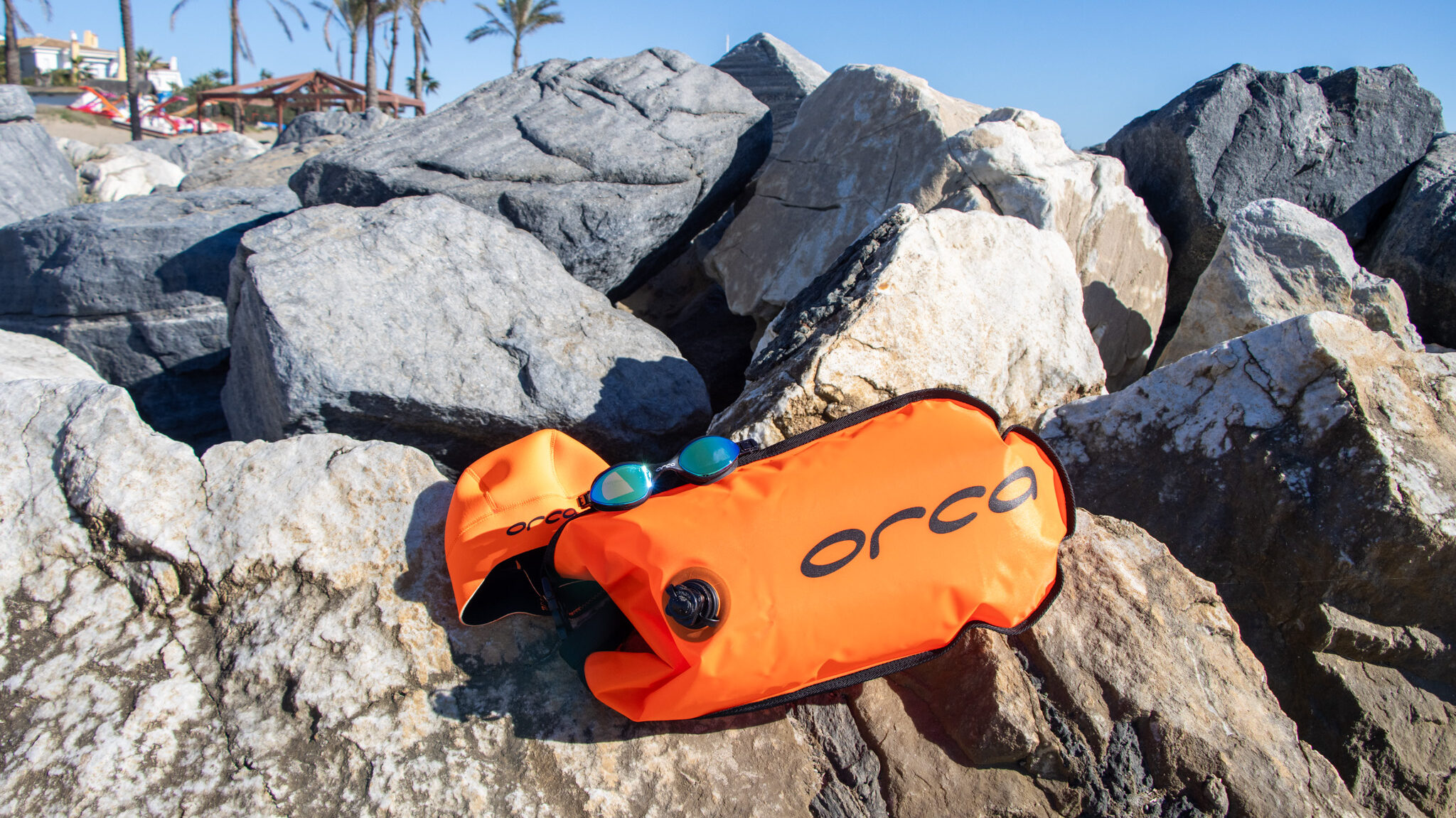 Swimming goggles, swim cap, and swim buoy in orange unique beach gear.