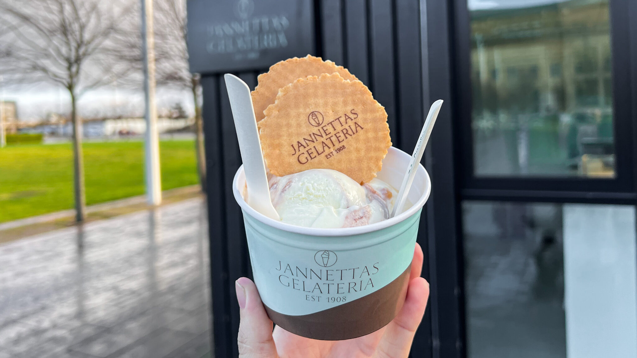 Ice cream in small tub with two wafers. 