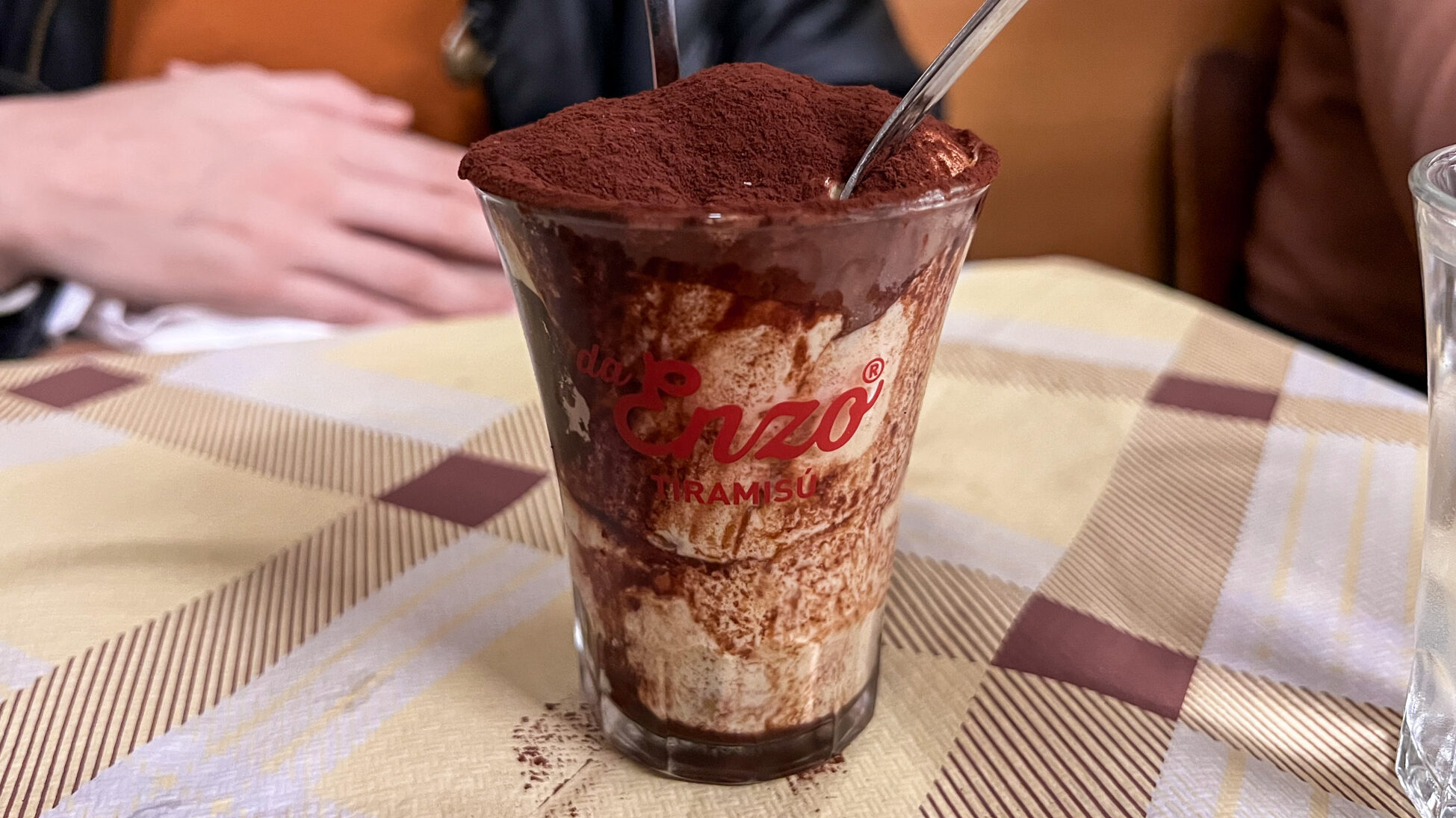 Tiramisu in restaurant served in tall glass.