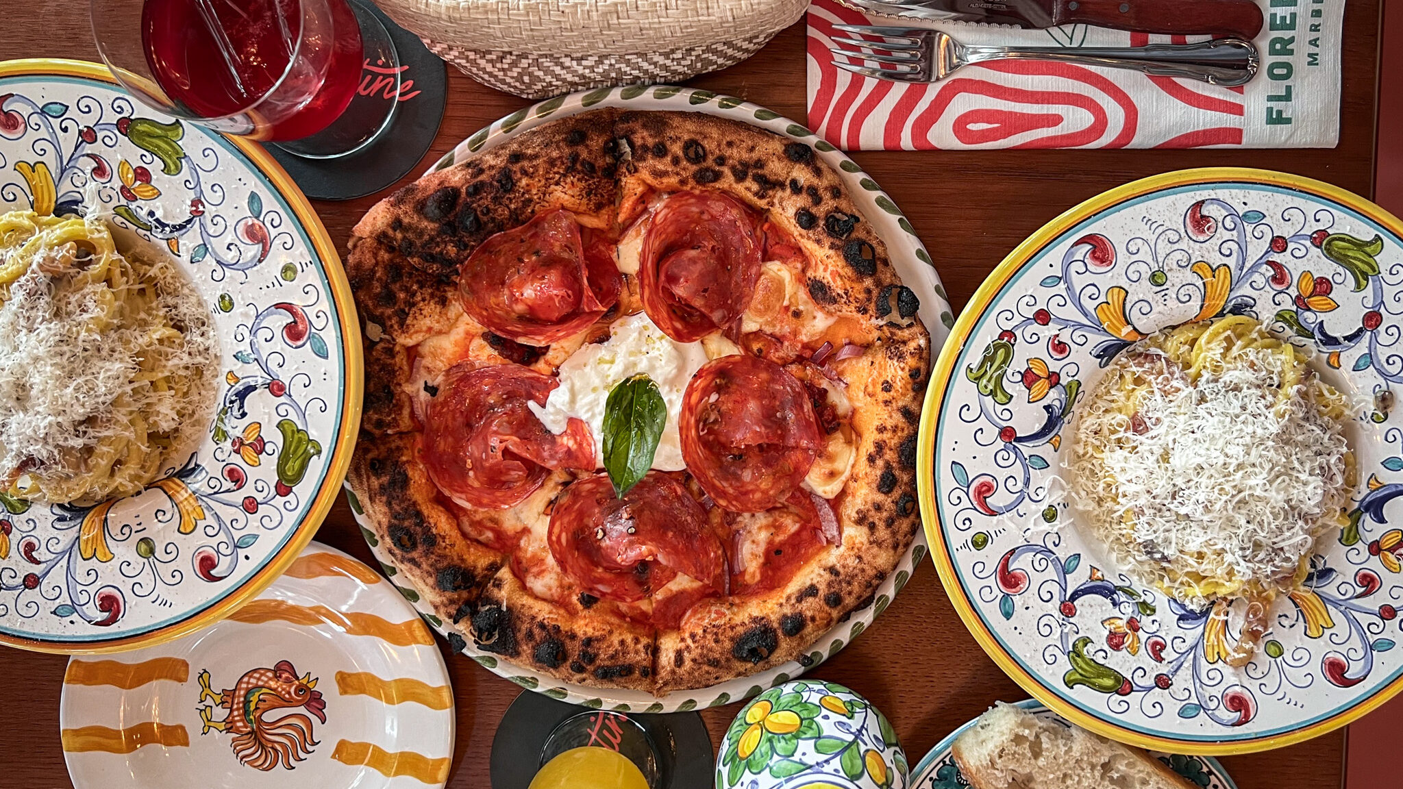 Pizza and carbonara dishes on wooden table.