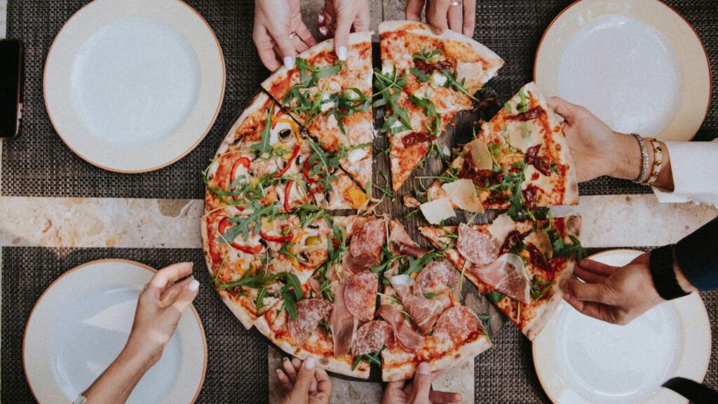 Pizza slices being taken by hands.