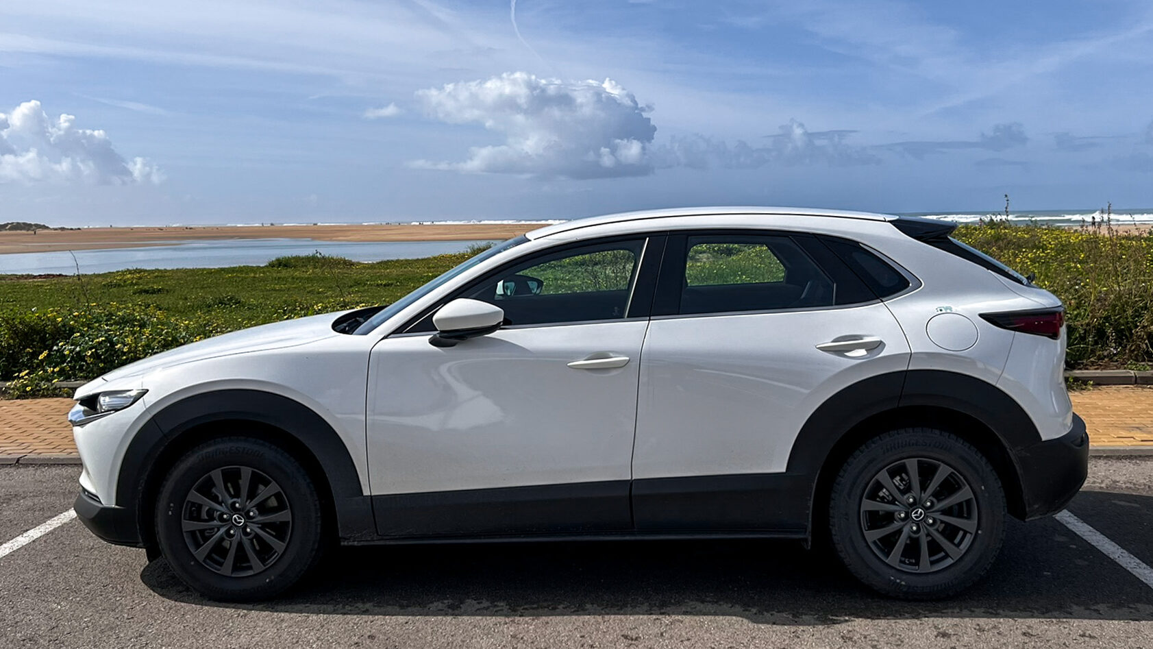 Helle Hollis Malaga | Krista the Explorer New white rental car in front of beach.