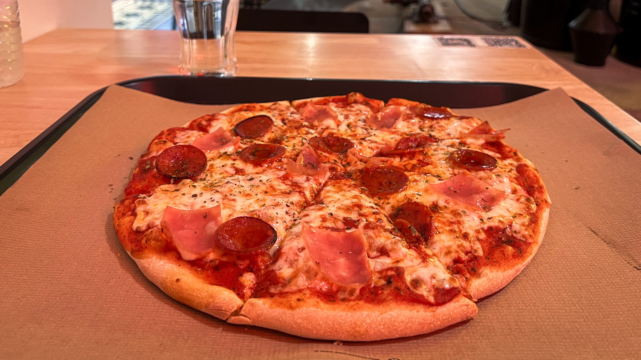 Pikend Pizza Zafra | Krista the Explorer Pepperoni and ham pizza served on paper sheet.