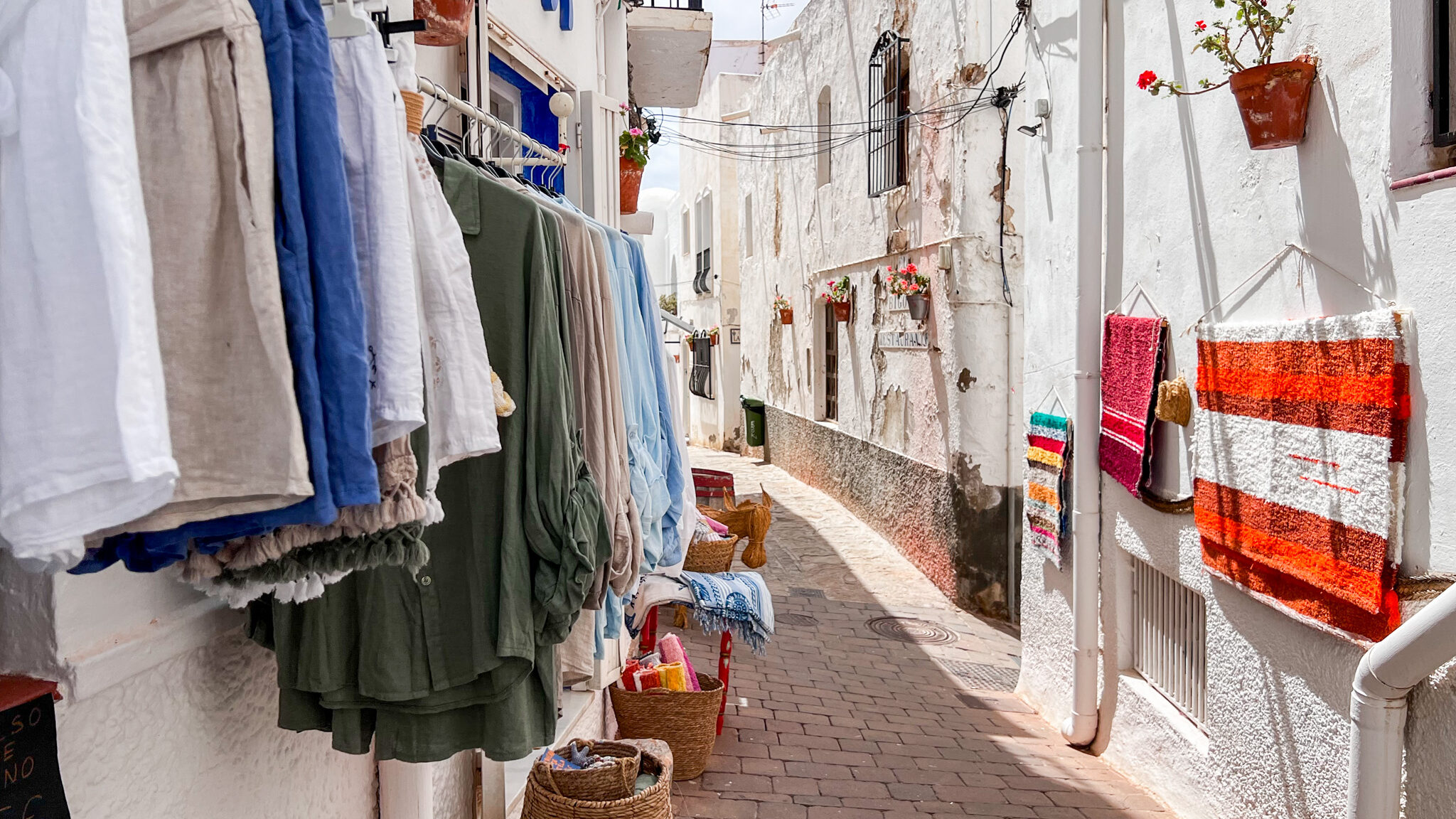 Whitewashed street with clothing shops.