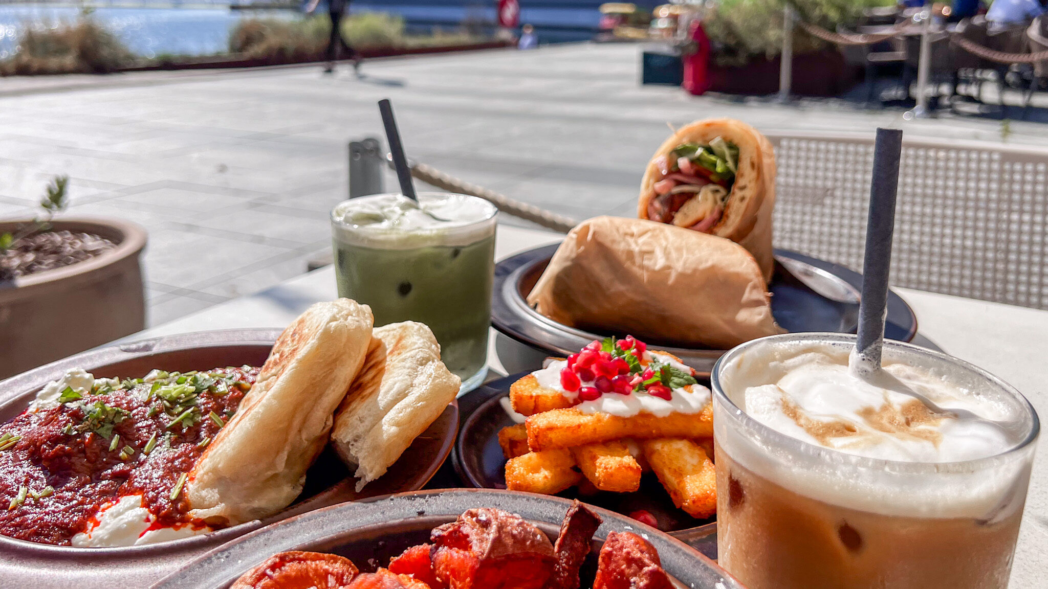 KUMI Oslo | Krista the Explorer Selection of brunch dishes and coffee on outside table next to water.