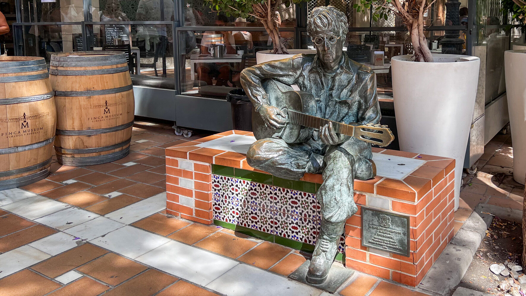 Statue of John Lennon with guitar in small square.