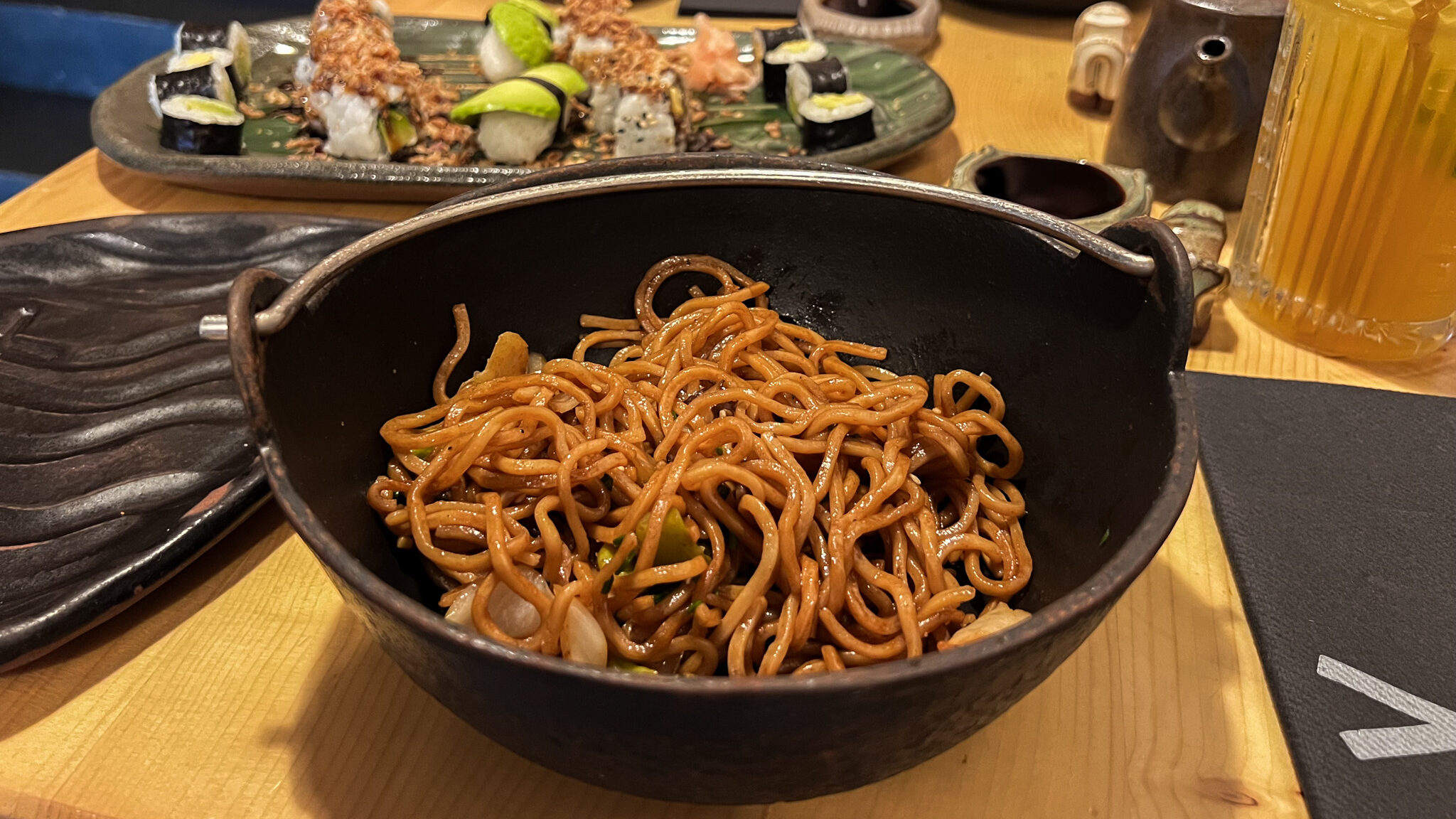 Deep bowl of noodles and plate of vegetarian sushi.