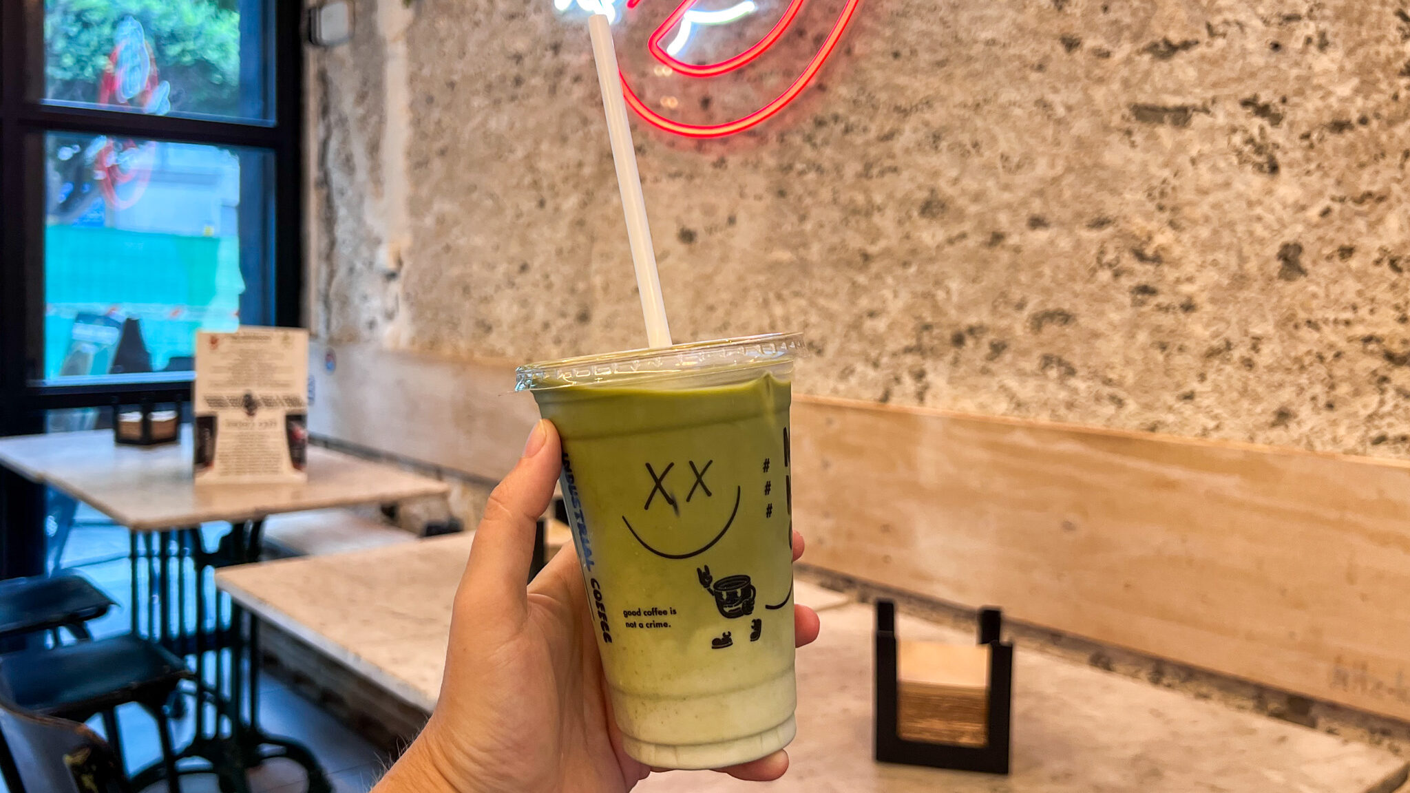 Iced matcha latte with straw inside coffee shop.