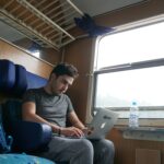 Nomad sitting on trail typing on his laptop.