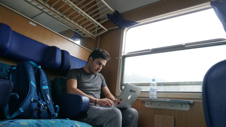Nomad sitting on trail typing on his laptop.