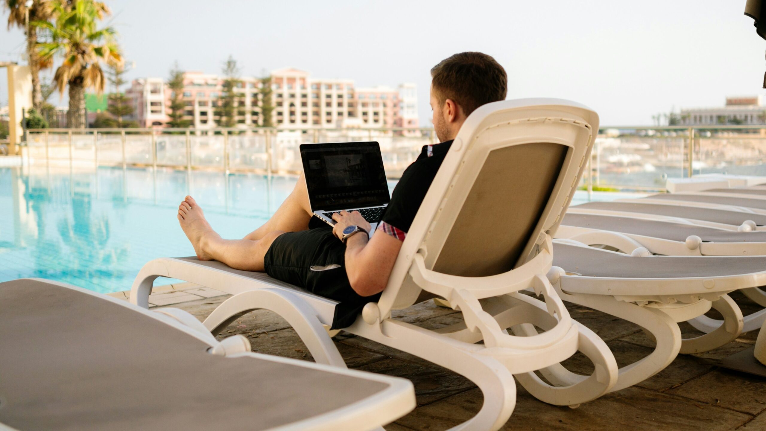 Nomad | Krista the Explorer Digital nomad working poolside on laptop.