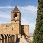 Fortress wall leading up to square tower.