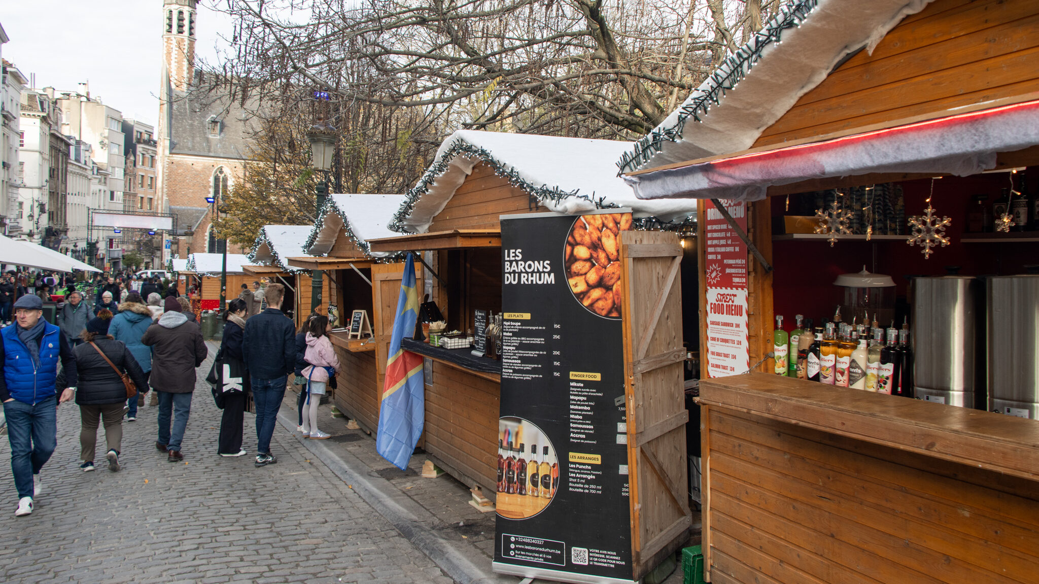 Street in Brussels lined with wooden Christmas market stalls.