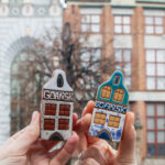 Two small ceramic Polish houses being held up.