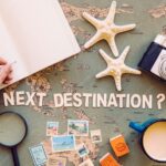 Flat lay of person writing in notebook on top of map.