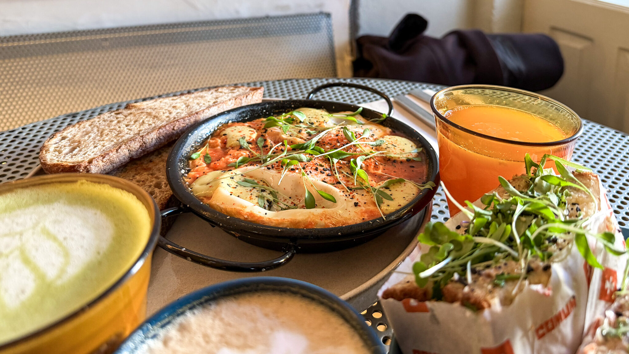 Shakshuka and breakfast wrap on table in cafe.